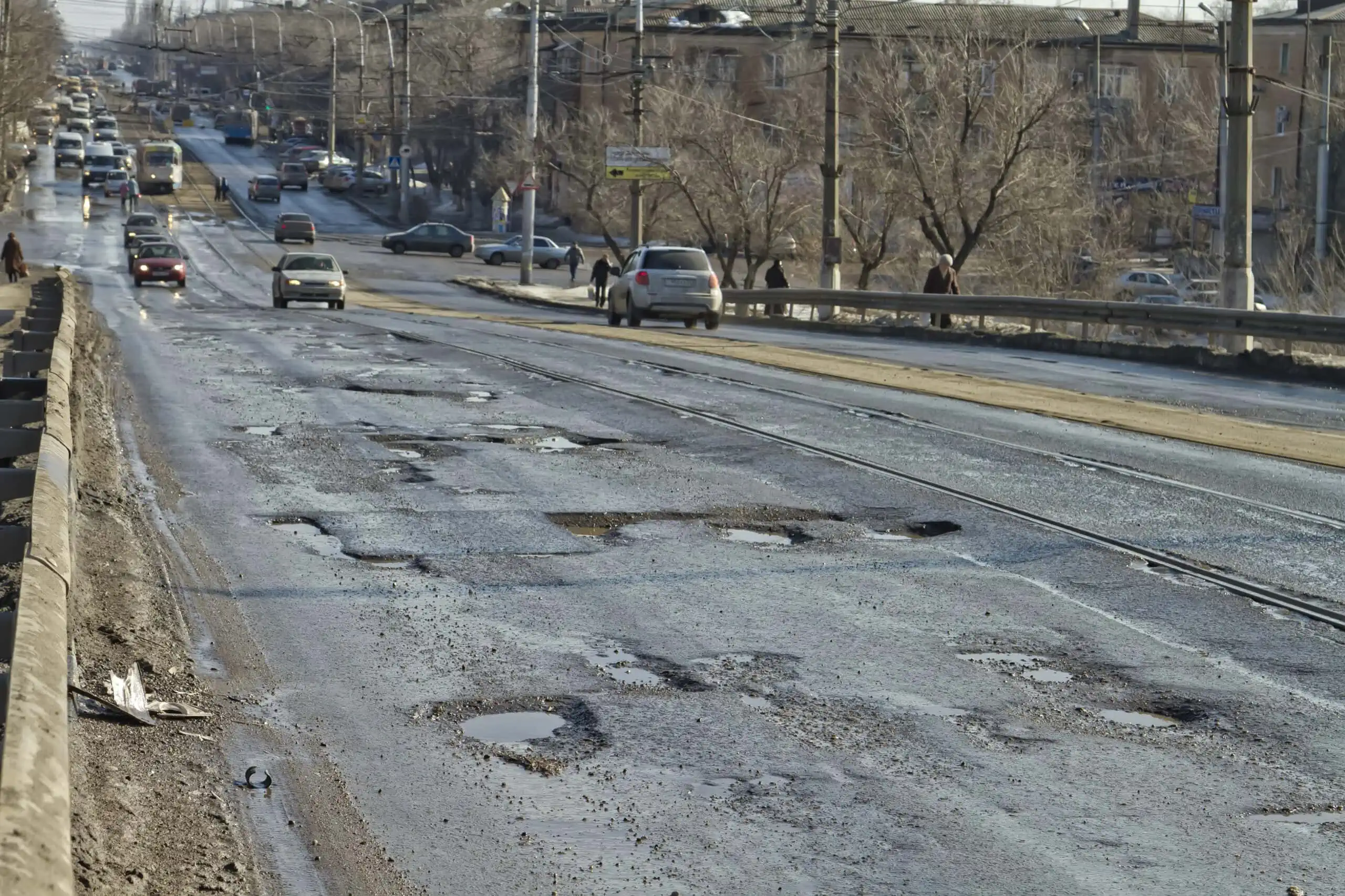 Stretch of uneven road with multiple potholes