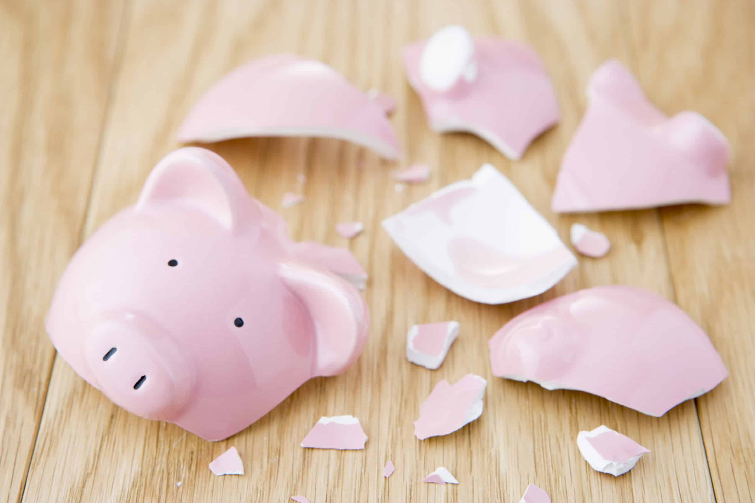 A broken pink ceramic piggy bank symbolizing failure to budget money