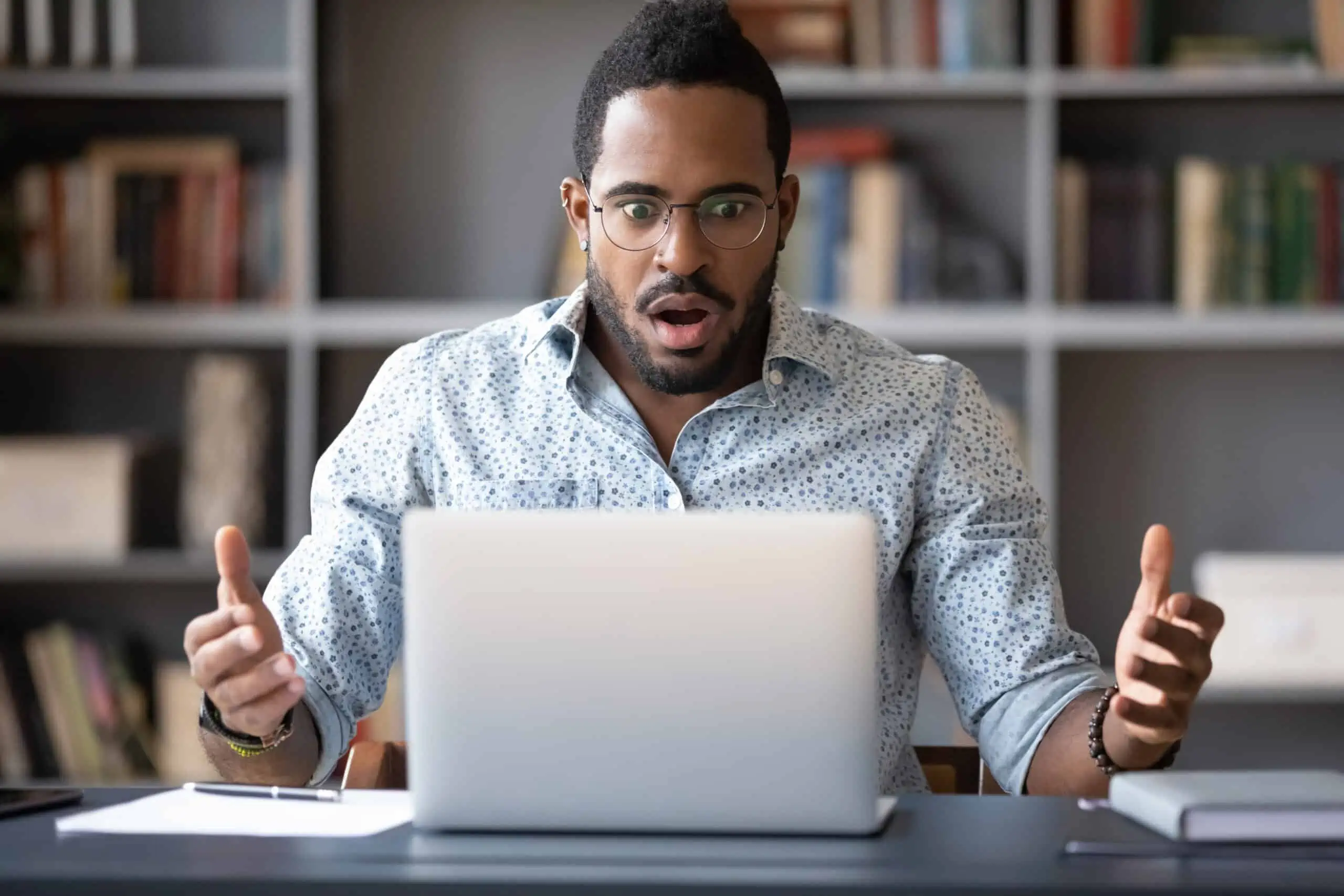 Black male surprised trying to figure out Instacart prices for grocery delivery service on a laptop