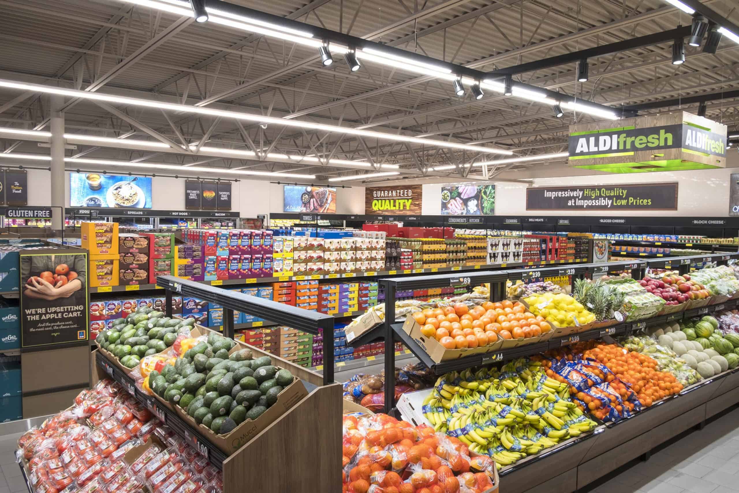 The fresh produce section of Aldi stores showcasing tomatoes, avocados, and oranges