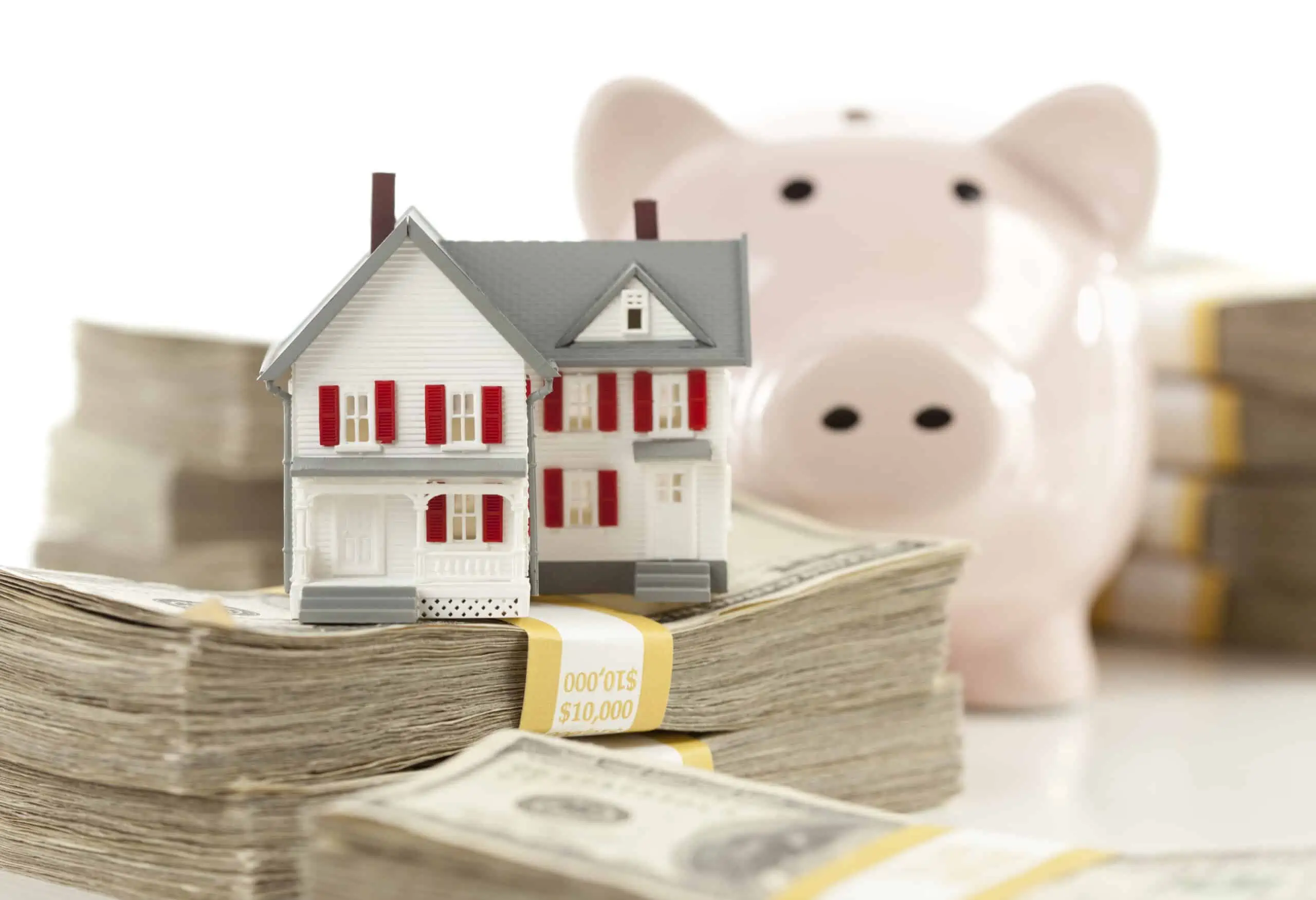 HELOC being represented by a toy house and piggy bank with banded stacks of hundred dollar bills Isolated on a White Background.