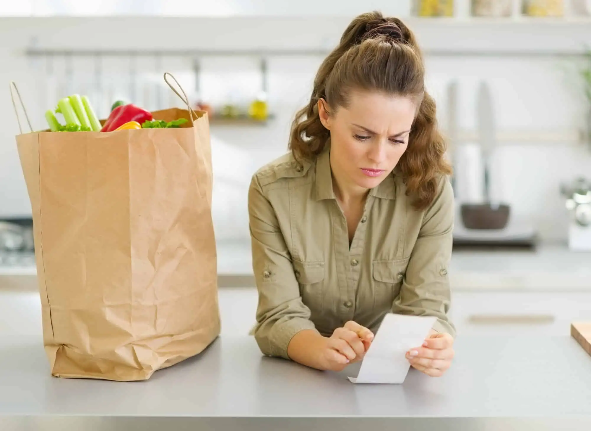Woman looking over Instacart receipt with concern after receiving grocery delivery service order.