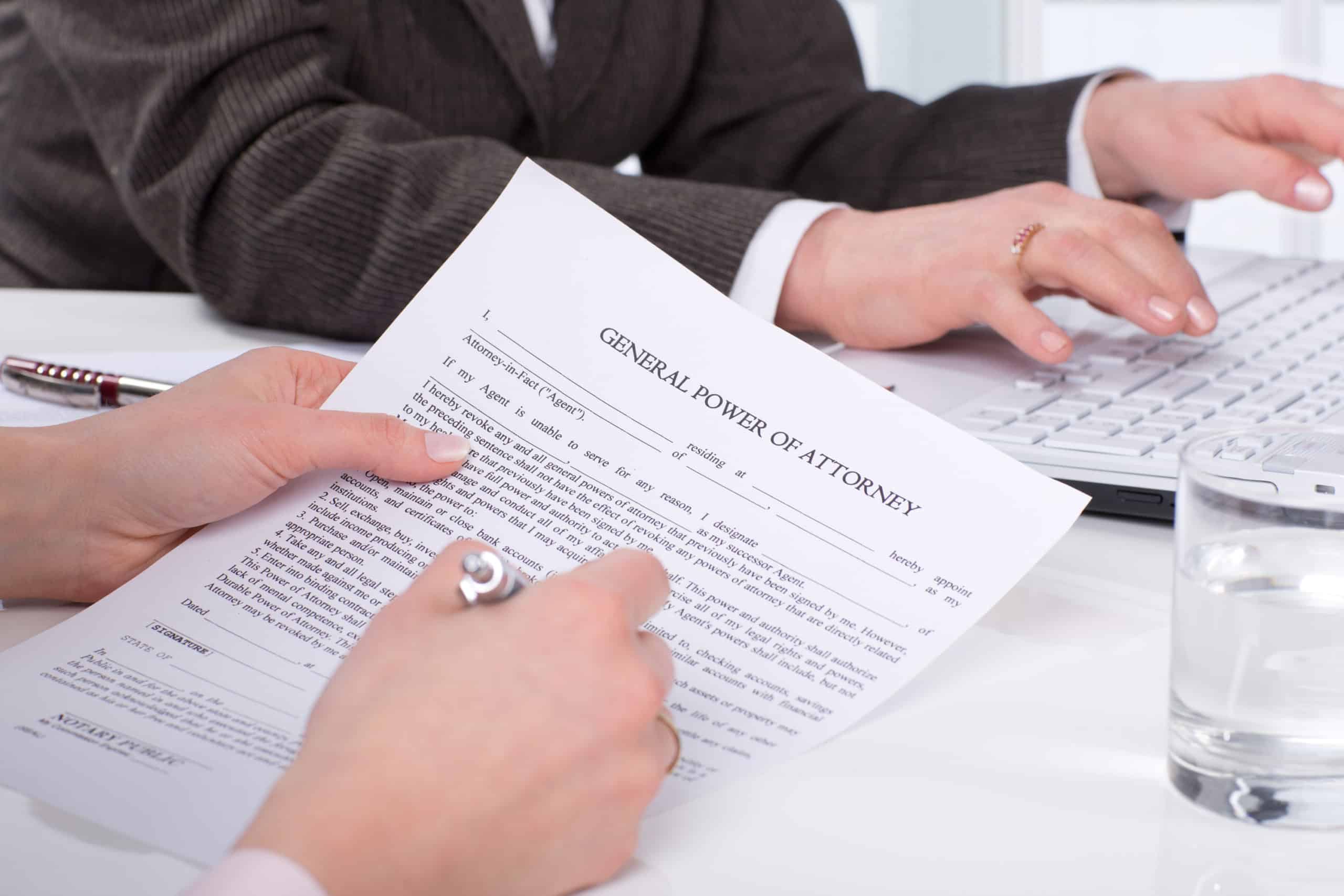Woman's hand signing Power of Attorney form during estate planning.
