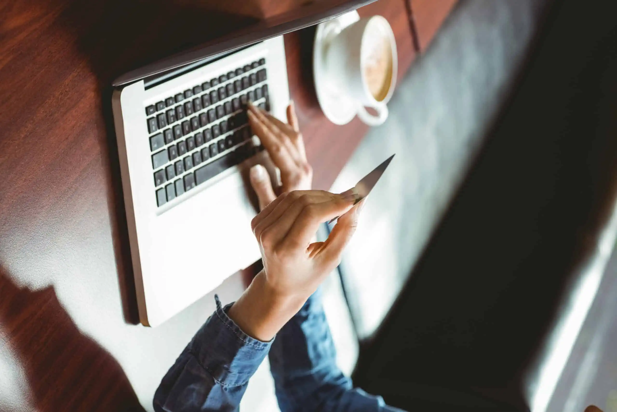 Caucasian woman entering her credit card info for a free trial on a laptop in a coffee shop