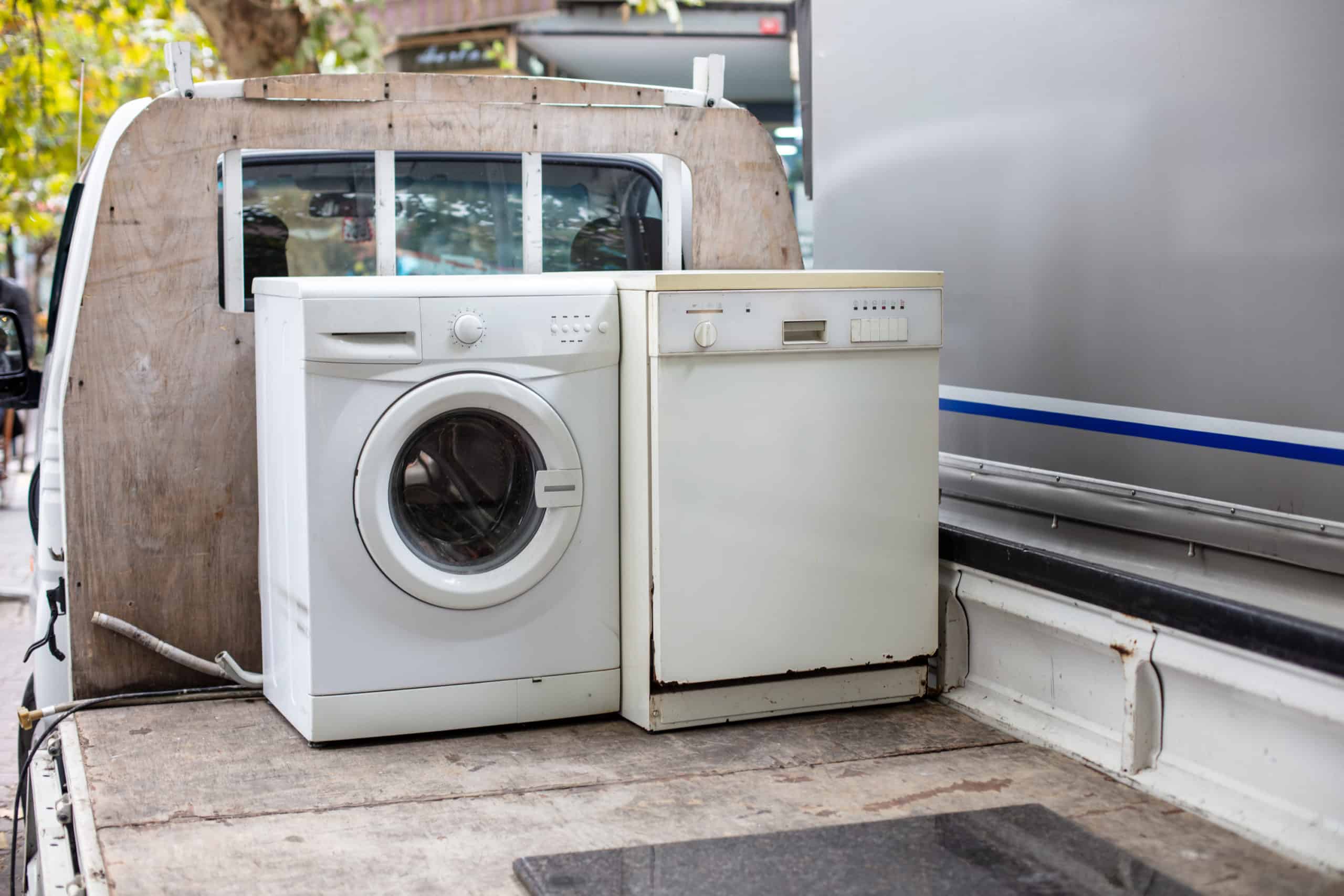 Old used washing machine and dishwasher on a flatbed truck to replace broken appliances for a person renting a home.