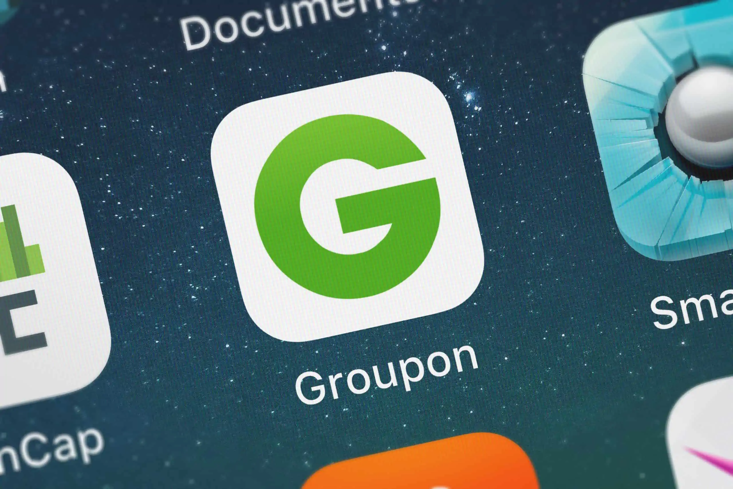 Groupon app on a cell phone screen is being used to find a discount on a restaurant for a first date.