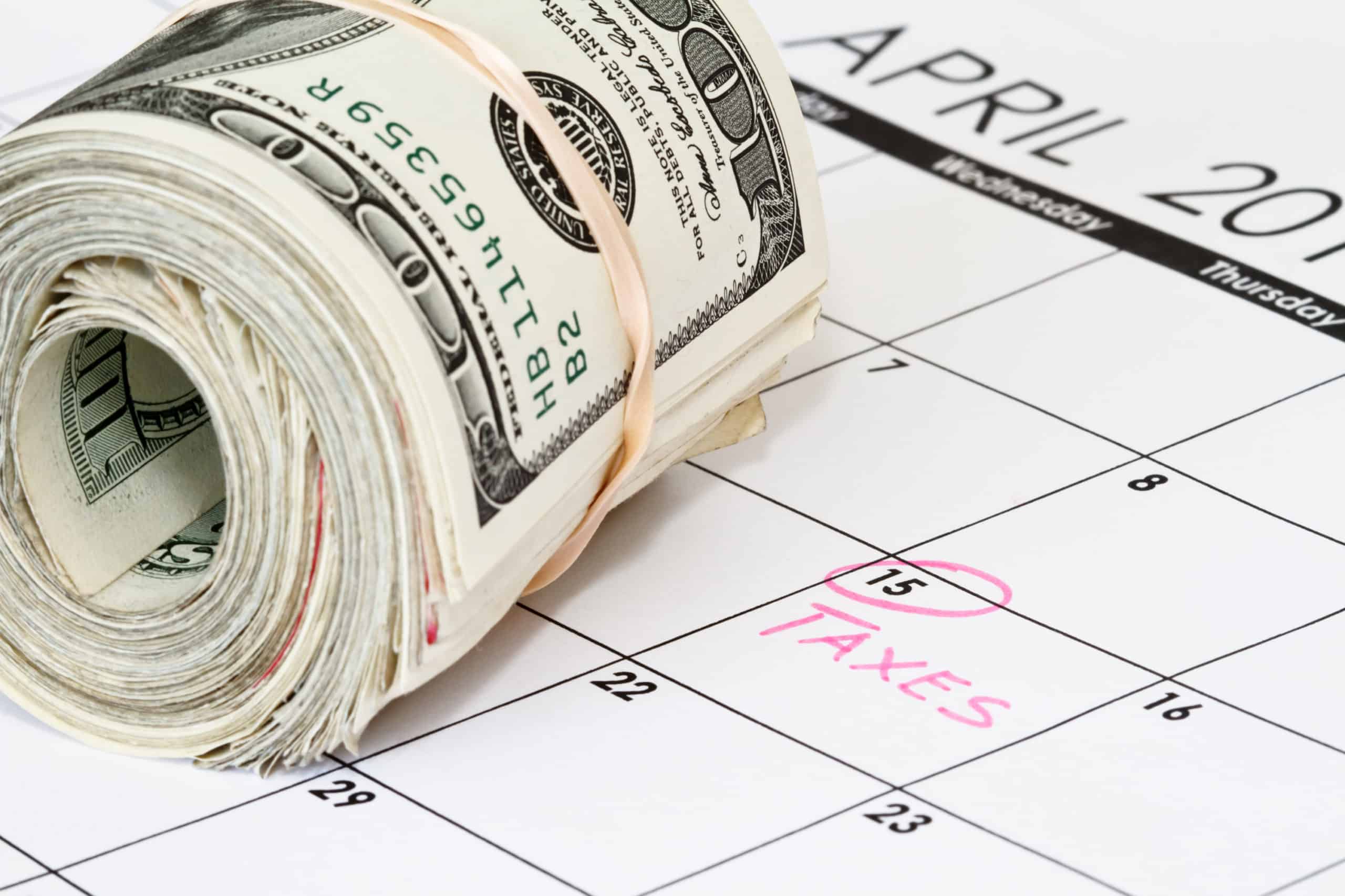 Income Tax Return Basics To Know To Avoid Worry 2 Tax filing deadline, April 15, circled on a calendar in pink with "taxes" written on it with a roll of $100 bills on top